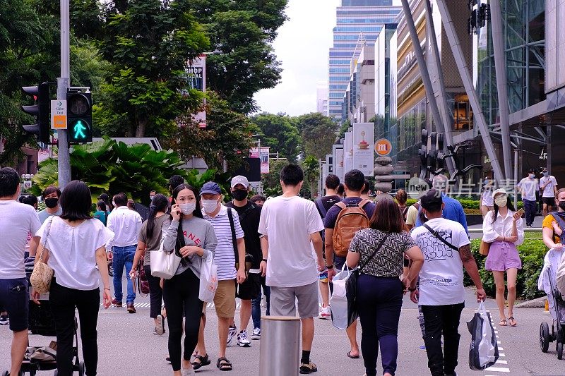 新加坡Sep2020戴口罩的人过马路(选择性聚焦)。2期断电后乌节路人群聚集;Covid-19冠状病毒的爆发。