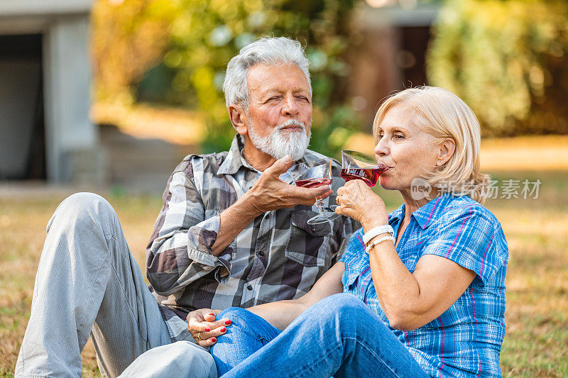 老夫妇在后院喝着葡萄酒。