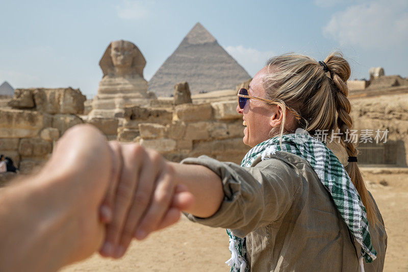 一对夫妇在埃及旅行，他们手牵着手跟着对方