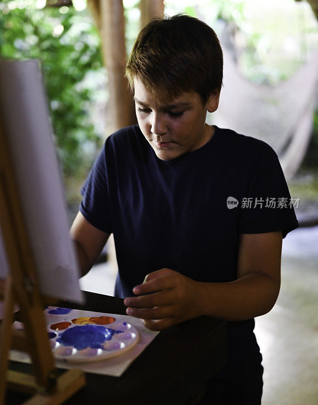 拉丁少年在美术课上或工作室用颜料在画布上创作艺术