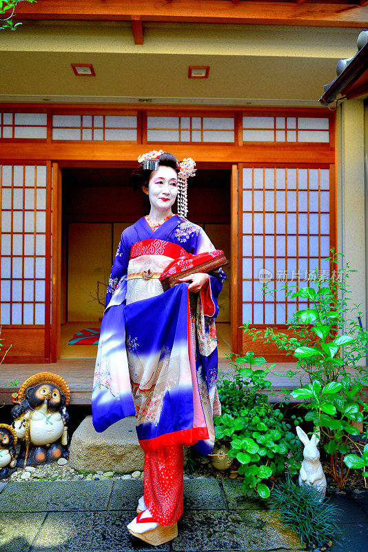 穿着舞妓服装的日本女人站在京都艺妓屋的庭院里