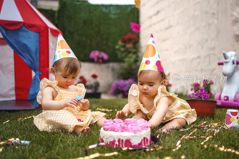 双胞胎姐妹在草地上玩在他们的第一个生日聚会