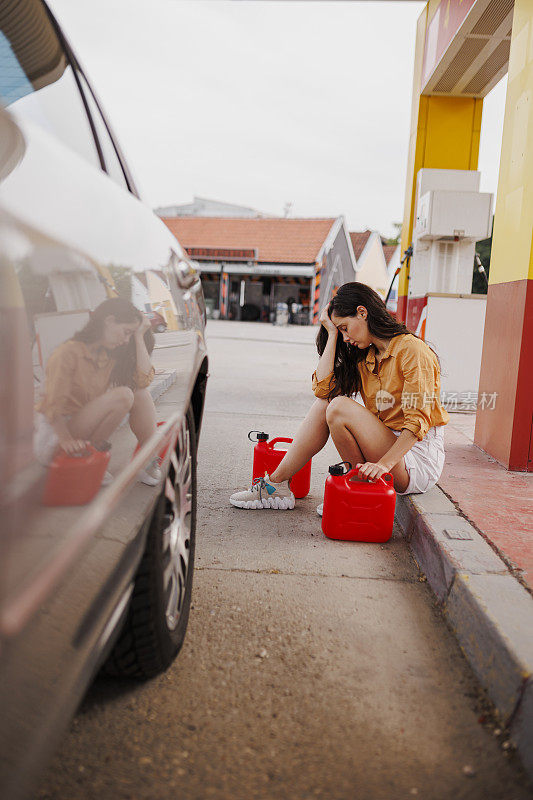 加油站里拿着油罐的女人心烦意乱