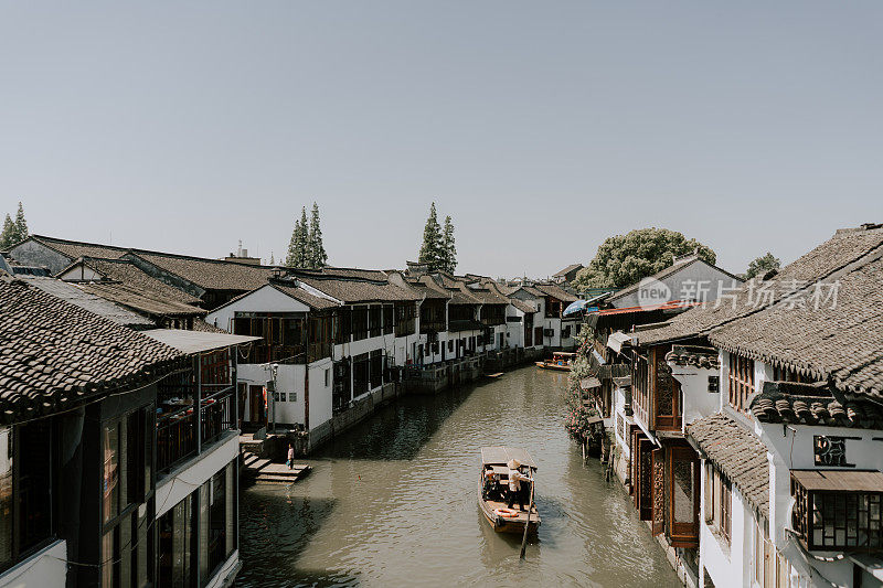 在中国上海的一个古老的中国村庄旁边，渔民们划着他们的传统船只