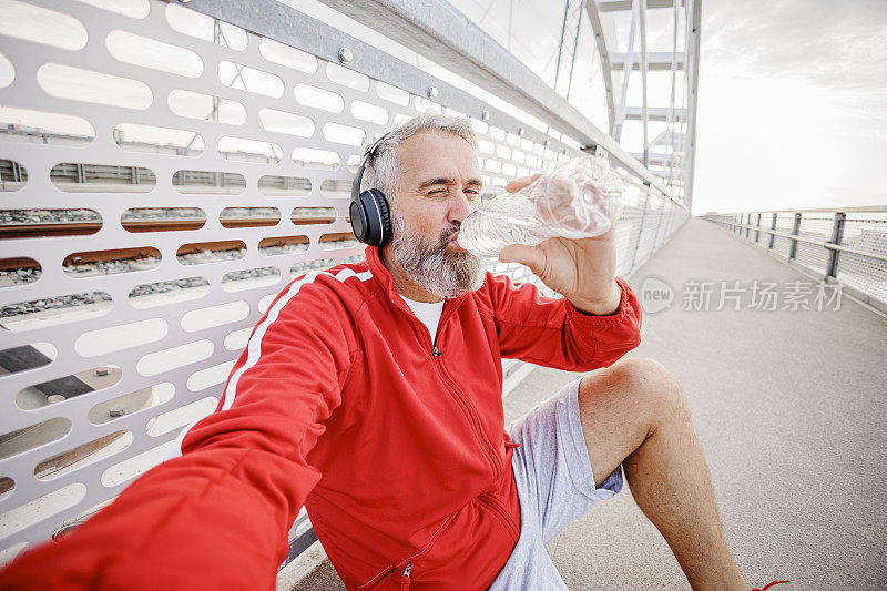 成年男子在户外高强度运动后喝水和休息的自画像