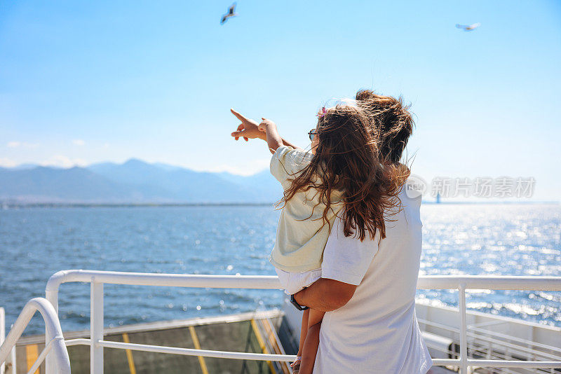 女孩和她的父亲坐船旅行，看着海鸥