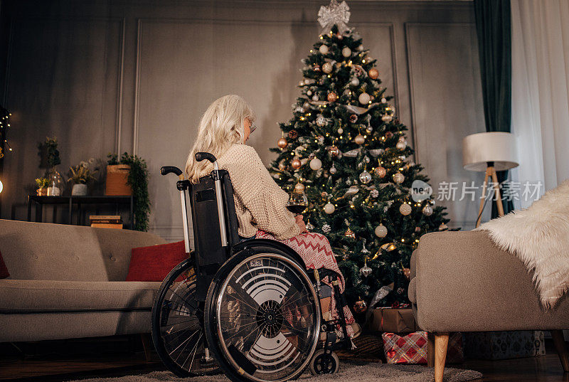 坐在轮椅上的老年妇女在圣诞树旁