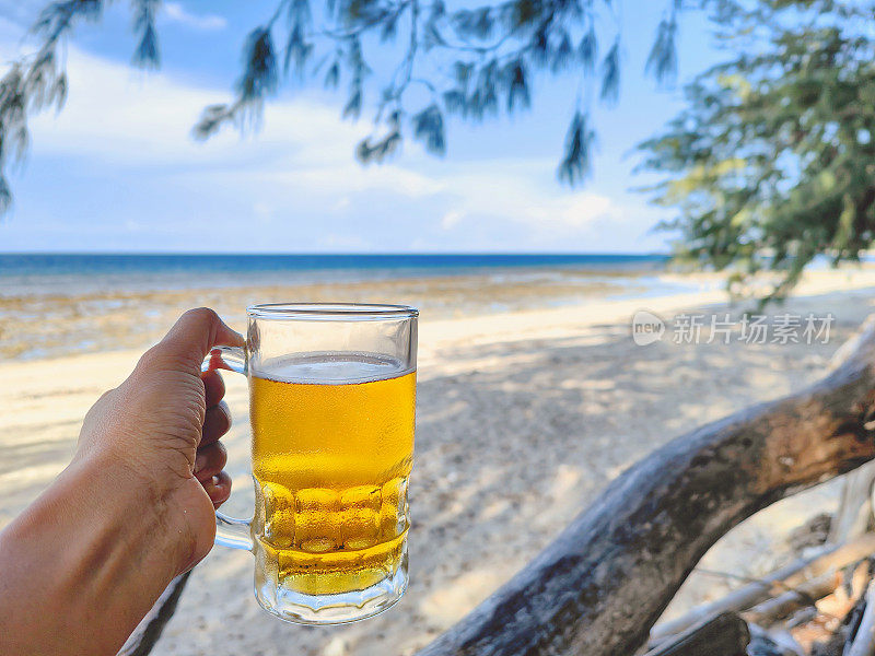 难以辨认的女性双手在海滩上举杯