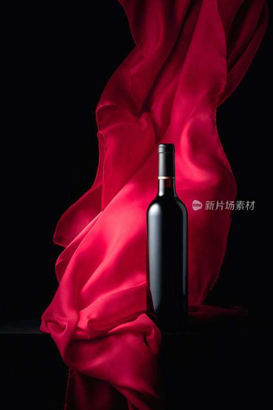 一瓶红酒和飘动的红布。