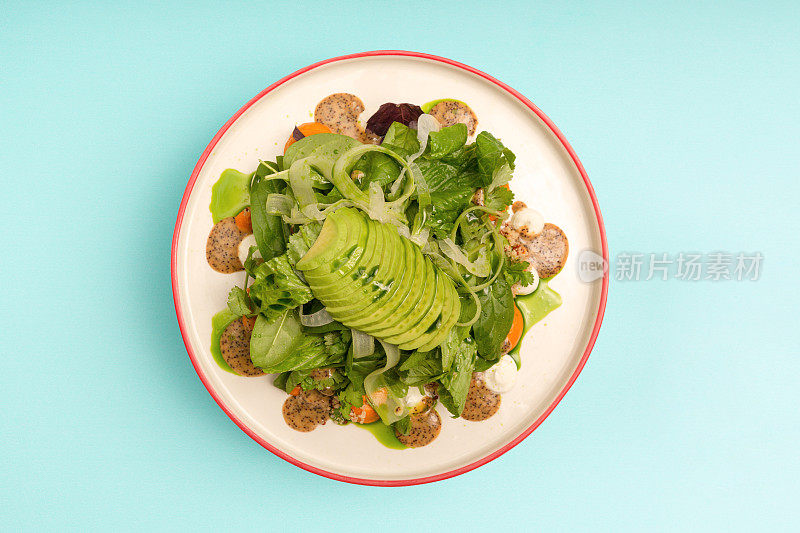 绿色素食餐盘，有鳄梨、菠菜、叶子和芹菜。前视图。
