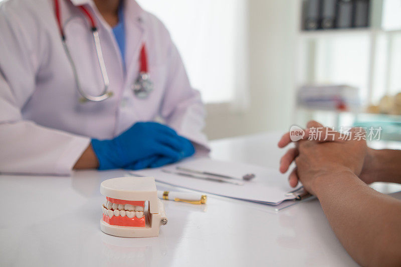 牙医手里拿着假牙，向病人展示问题牙齿的位置，并向病人解释如何治疗牙齿，以便病人理解。文本复制空间