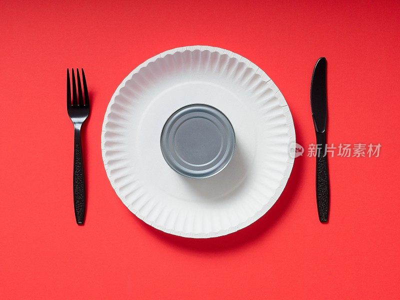 未开封的金枪鱼罐头放在纸盘上，红色的塑料器皿