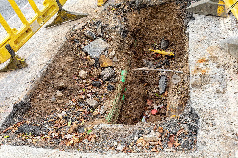 英国的道路工程正在挖掘当地的柏油路面，以修复地下的公用管道，并设置安全屏障和标志