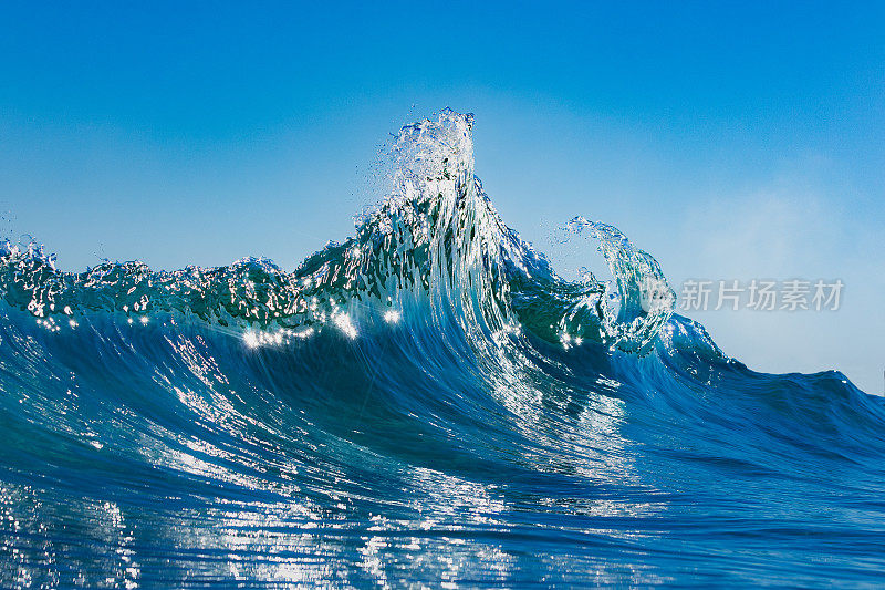 明亮的蓝色波浪在晴朗的日子里达到顶峰