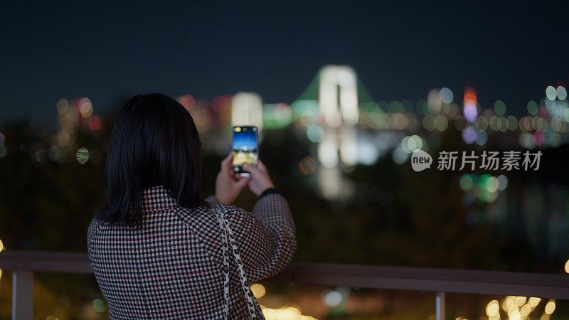 一名女子在台场拍摄东京夜景的照片和视频