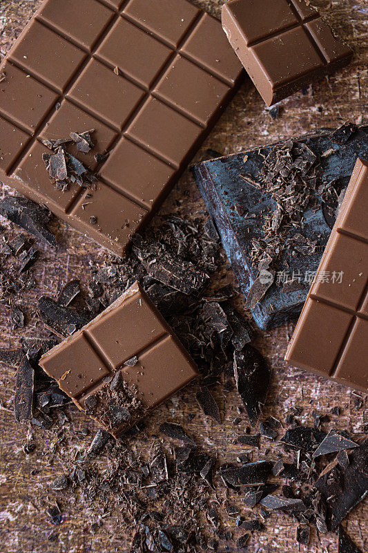 全帧图像的巧克力棒，牛奶巧克力块和黑巧克力块磨碎的刨花在苦恼的棕色背景，抬高视图