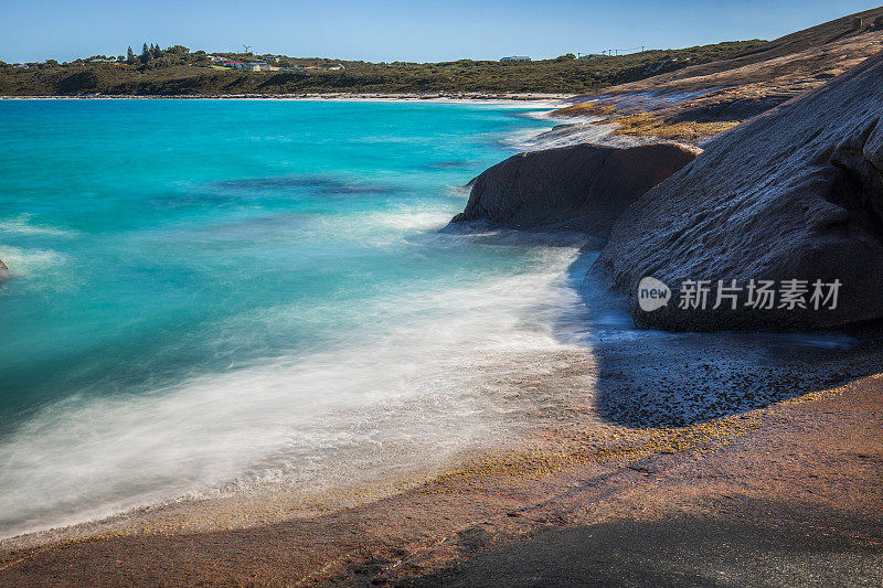 慢快门海岸场景，海水蓝色的海浪轻轻地冲刷着岩石