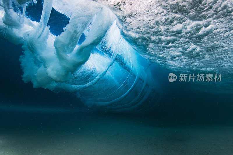 在清澈的海水中，海浪拍打着沙滩，水下的景色一览无余