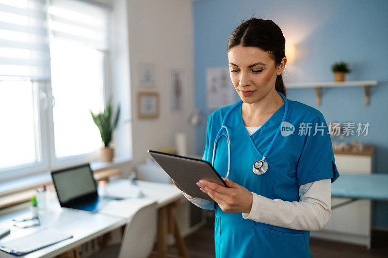 穿着蓝色医疗服的女护士，在授职时使用电子平板电脑
