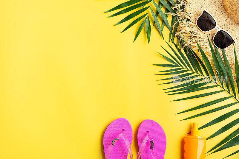 度假旅游规划简单的主题草帽，太阳镜，人字拖和棕榈叶在统一的黄色背景平躺与复制空间