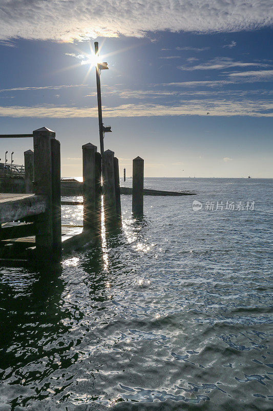 波光粼粼的大海和太阳从一个码头在沙洲普尔港，英格兰南部。