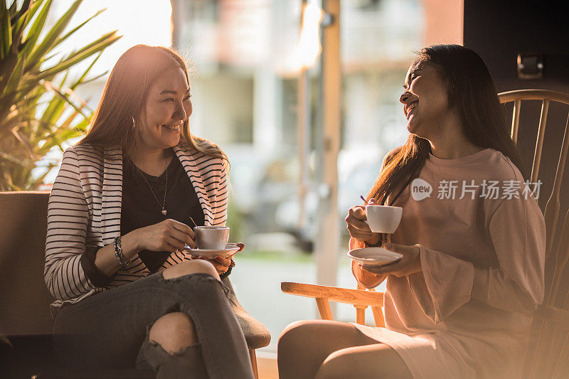 快乐的韩国女人享受着她们在咖啡馆的咖啡和彼此交谈。