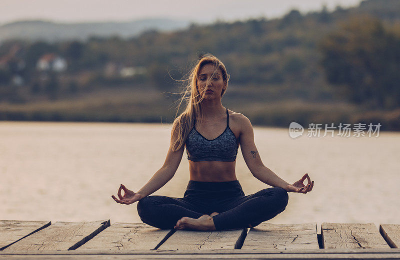 健康和运动的年轻女子在湖边做瑜伽