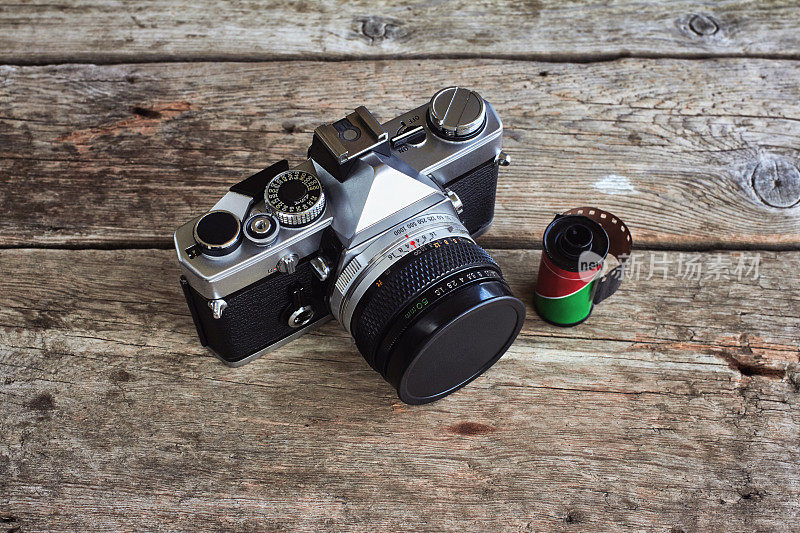 复古单镜头反光专业胶片相机在木桌上有一卷胶卷