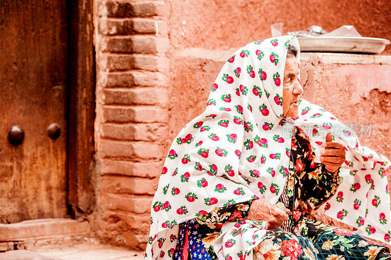 身着伊朗传统服饰的美丽老妇人在伊朗阿比尼亚古村落的街道上摆姿势