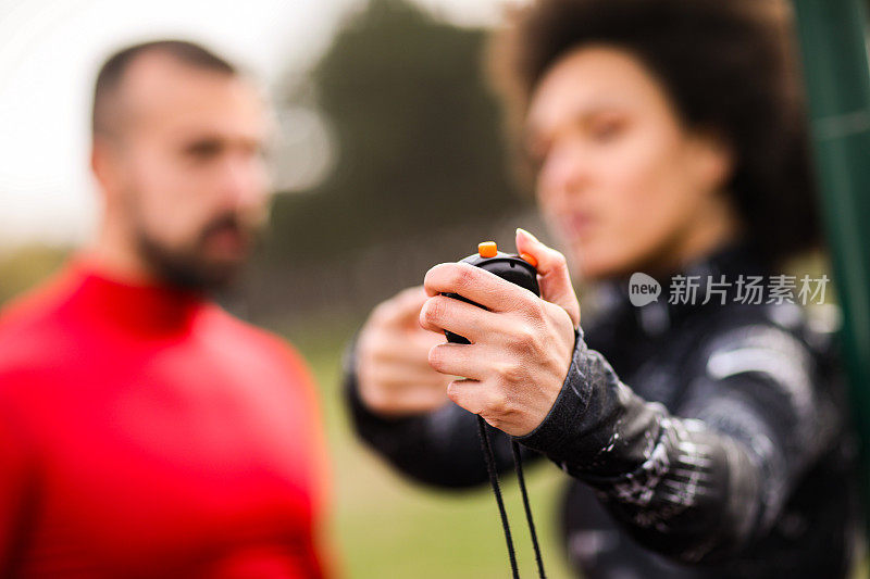 女私人教练用秒表显示她的男客户的表现和时间