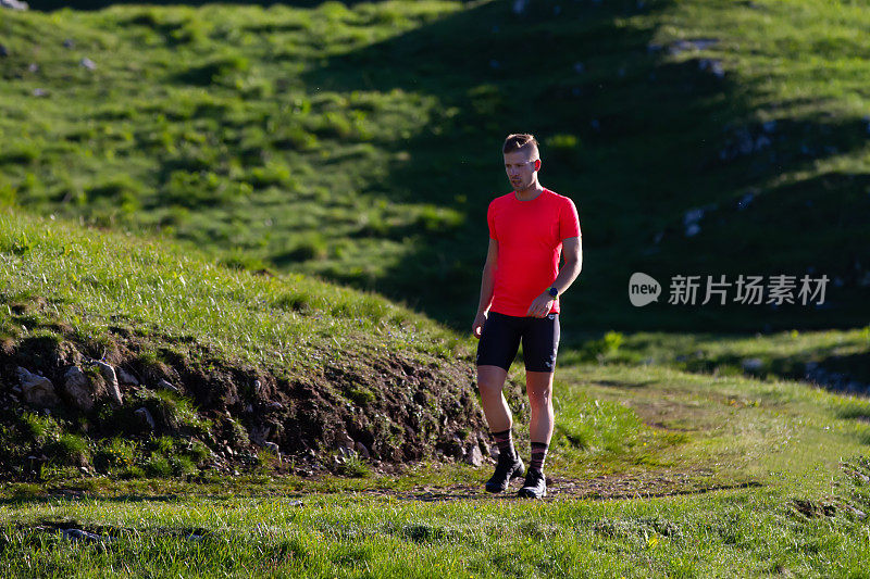 日出时，年轻的男运动员在山上训练跑步