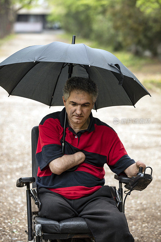 在雨天坐电动轮椅的残疾人在移动