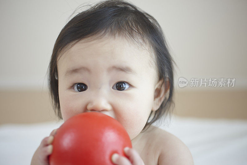 小女孩把红球放到嘴边的肖像