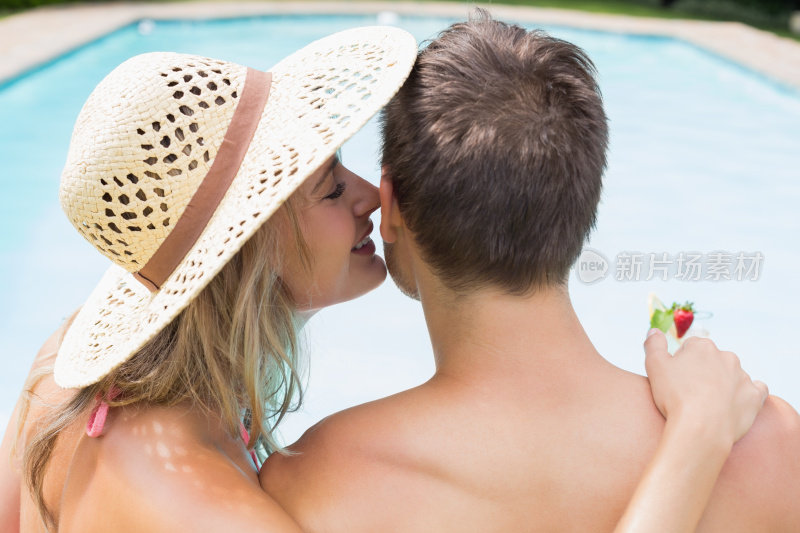 女人在泳池边对着男人的耳朵低语