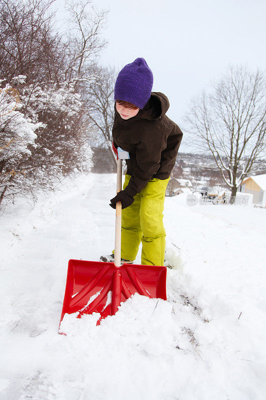 孩子在缤纷的冬天穿铲雪