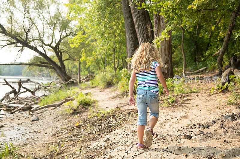 小女孩走在密西西比河岸边的沙路上