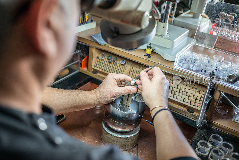 专业的宝石镶嵌珠宝工艺实验室:用显微镜工作的人