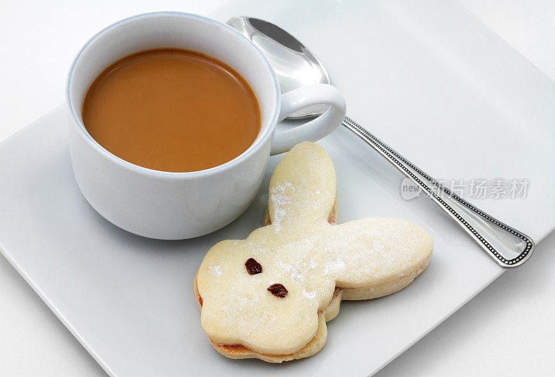 兔子形状的饼干在盘子里，还有一杯咖啡和一个勺子
