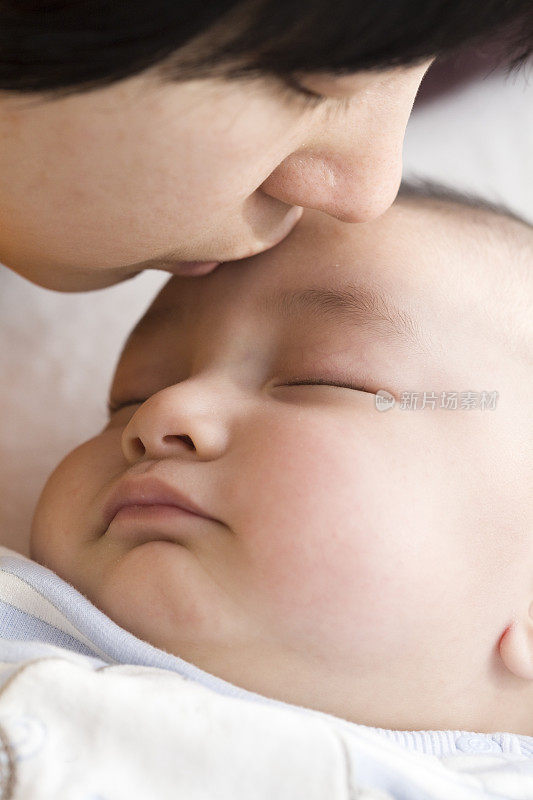 妈妈亲吻熟睡的婴儿