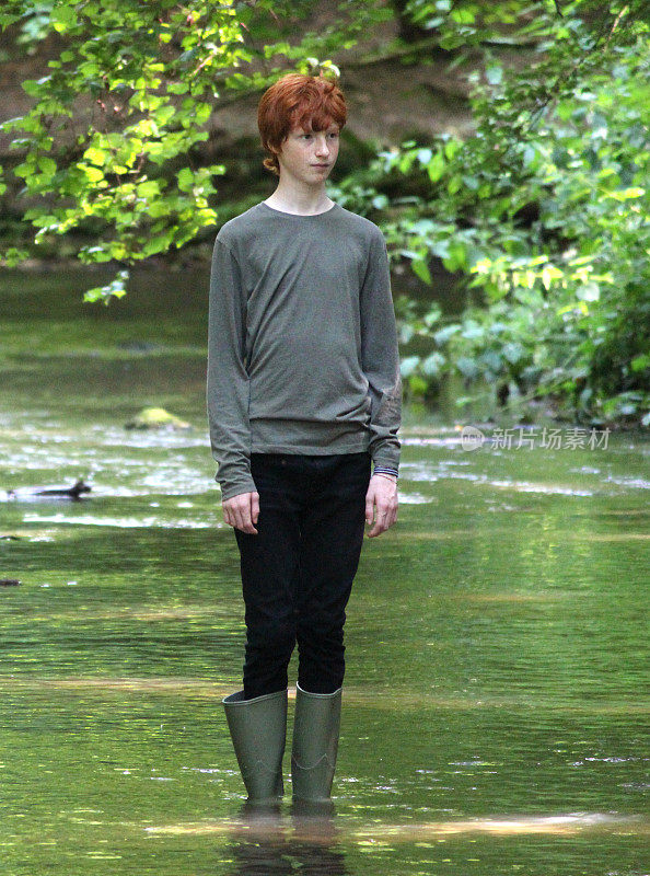 穿着绿色长筒靴的男孩在浅水中涉水