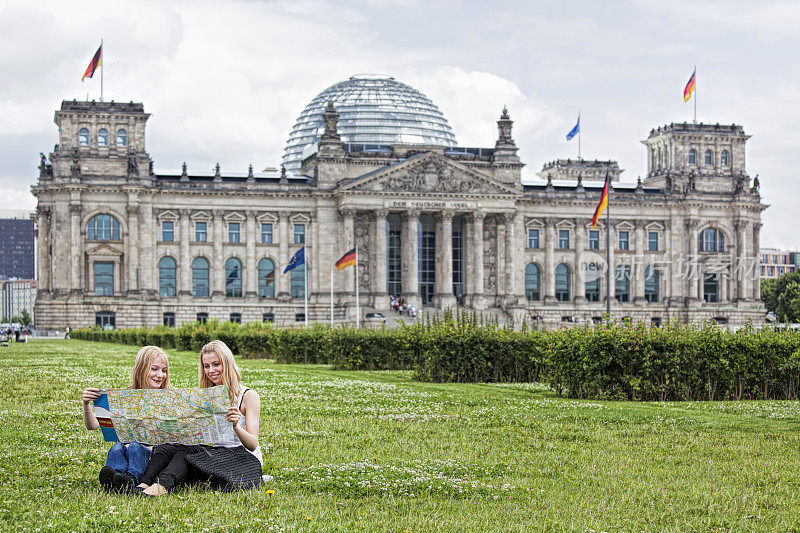 两名年轻女子坐在柏林国会大厦的草地上