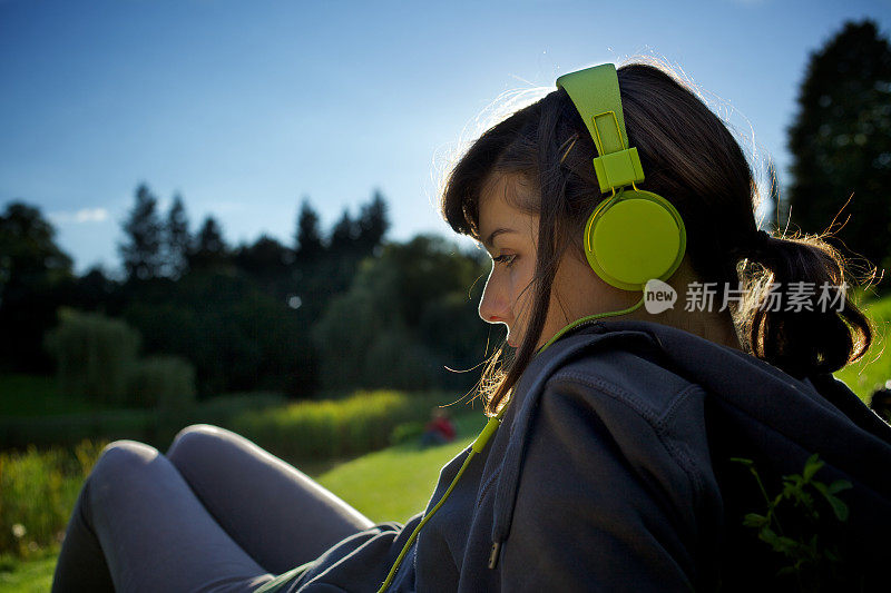 少女戴着大大的绿色耳机躺在草地上