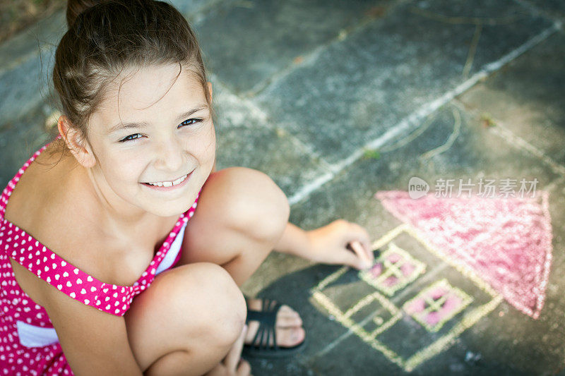 穿粉红色衣服的女孩在地板上画了一座房子
