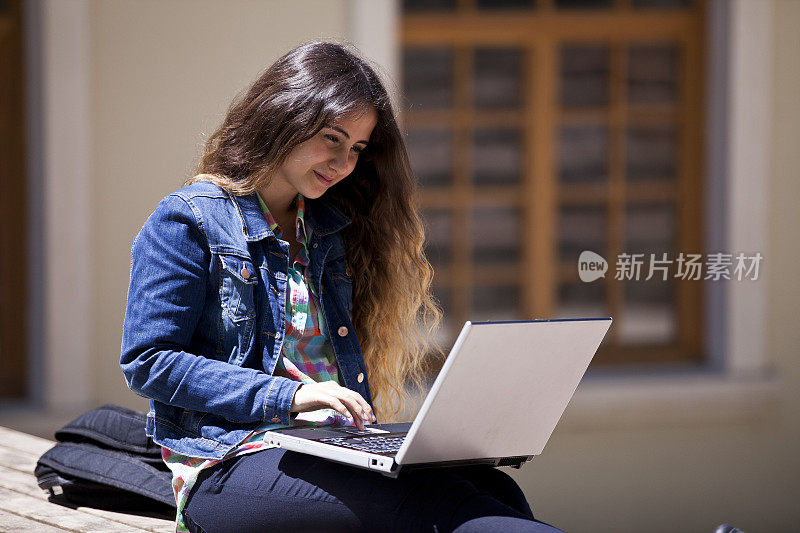 一个年轻女子在学校的花园里上网