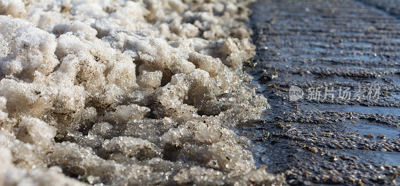 结霜的柏油路边缘，雪和雨夹雪的特写