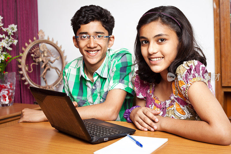 兴高采烈的印度少年弟弟妹妹用笔记本电脑做作业