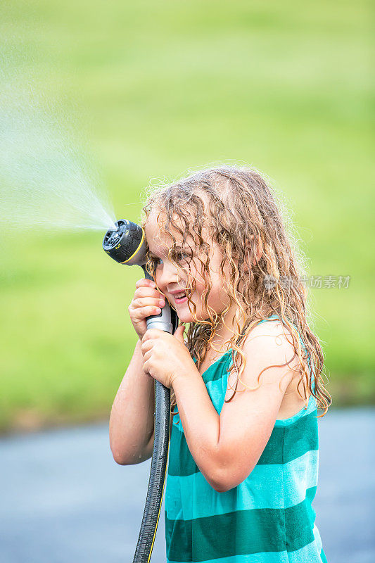 女孩用花园软管喷水