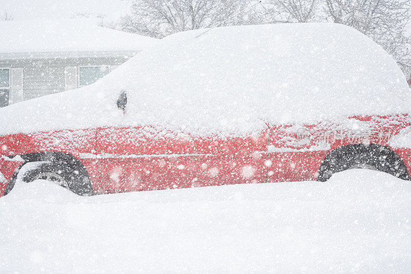 在冬季暴风雪中，红色的汽车被埋在雪中