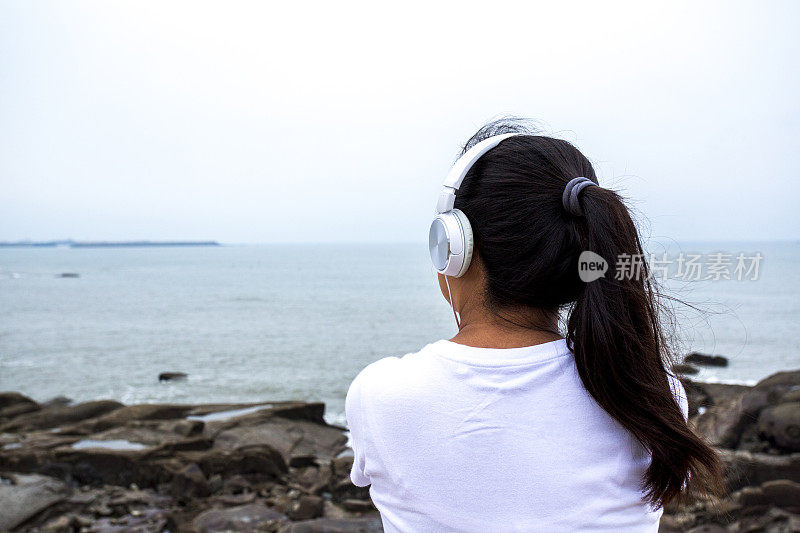 女孩戴着耳机，面朝大海