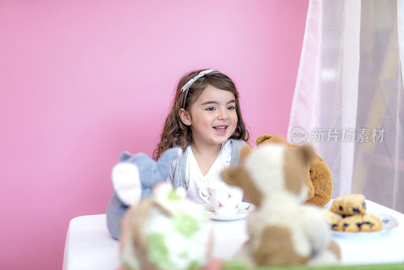 可爱的小女孩正在和她的毛绒玩具玩茶话会